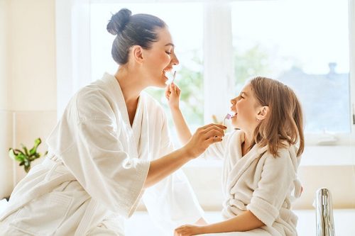 Mother and young daughter brushing each other's teeth