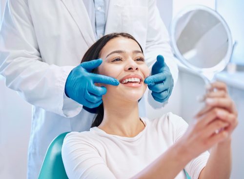 woman looks at smile in mirror at dentist's office