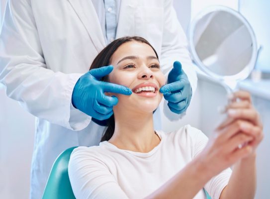 woman looks at smile in mirror at dentist's office